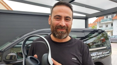 Hurman Tuncay zeigt die Kopfhörer, die sein Sohn von Andrew Garfield geschenkt bekommen hat. Im Hintergrund ist eines seiner Taxen zu sehen, Toni's ViP-Shuttle ist beim Fototermin unterwegs.  (Foto: Katrin Merklein)