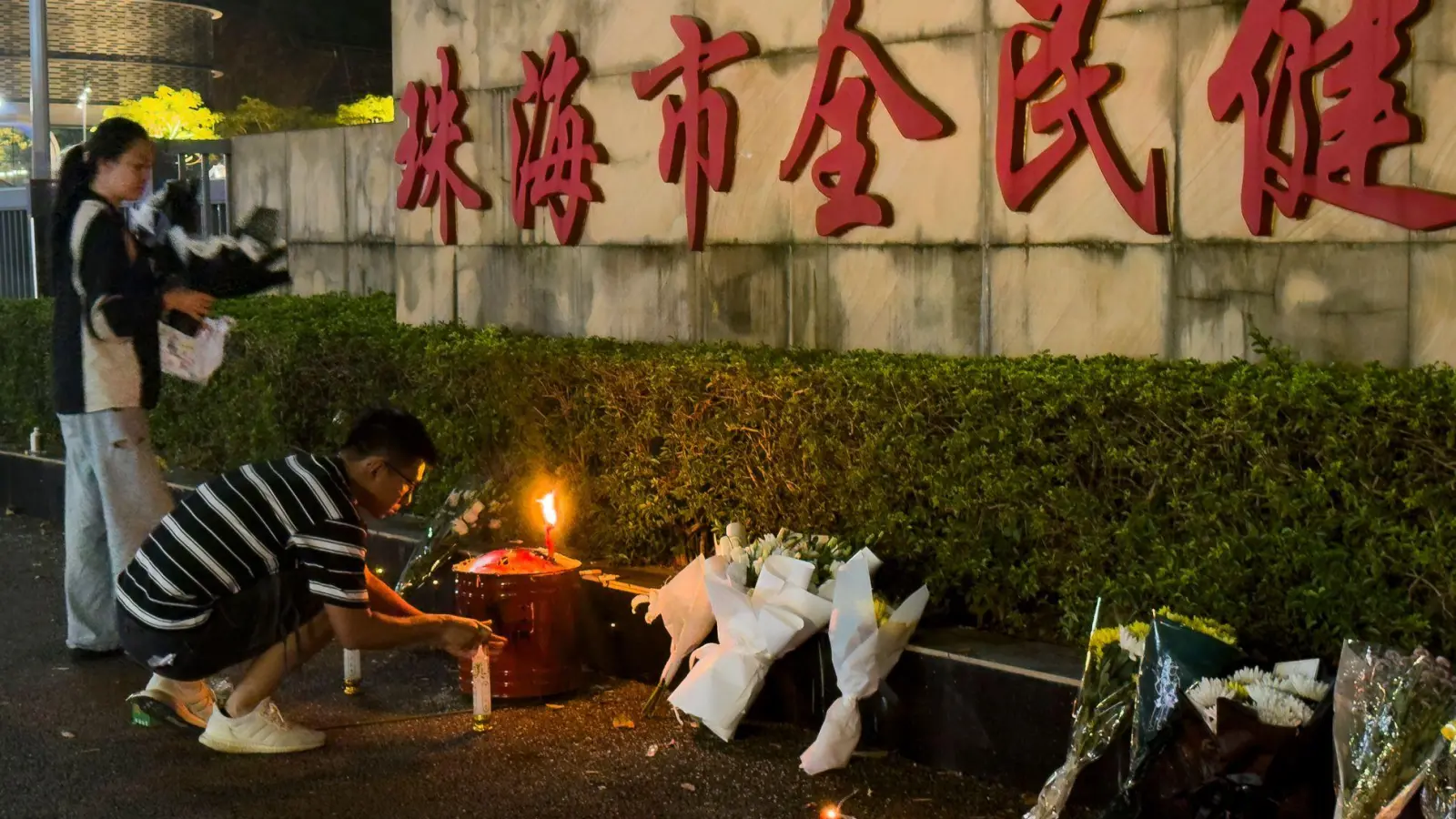 Menschen legen Blumen vor einem Sportzentrum nieder, wo ein Mann mit seinem Auto 35 Menschen tötete.  (Foto: Ng Han Guan/AP)