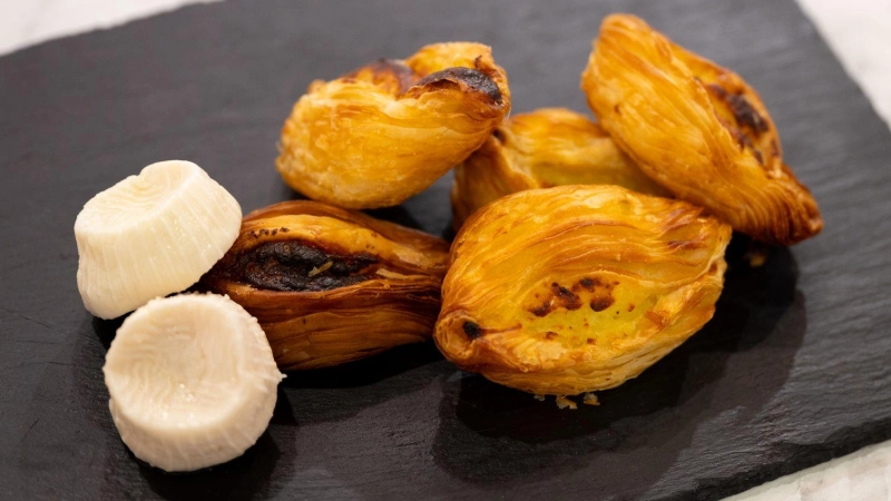 Sehen aus wie kleine Schiffchen: Die knusprigen Blätterteigtaschen heißen Pastizzi und sind das Nationalgericht von Malta. Sie werden wahlweise mit Ricotta, Erbsen-Curry oder dem maltesischen Gbejna-Käse (links im Bild) gefüllt.  (Foto: Nico Tapia/dpa-tmn)