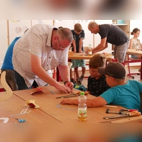 Die Kinder sind mit Feuereifer beim Bumerang-Bau. Hier geben Jeffrey Hausmann und Günther Simon (hinten) Hilfestellungen. (Foto: Daniel Ammon)