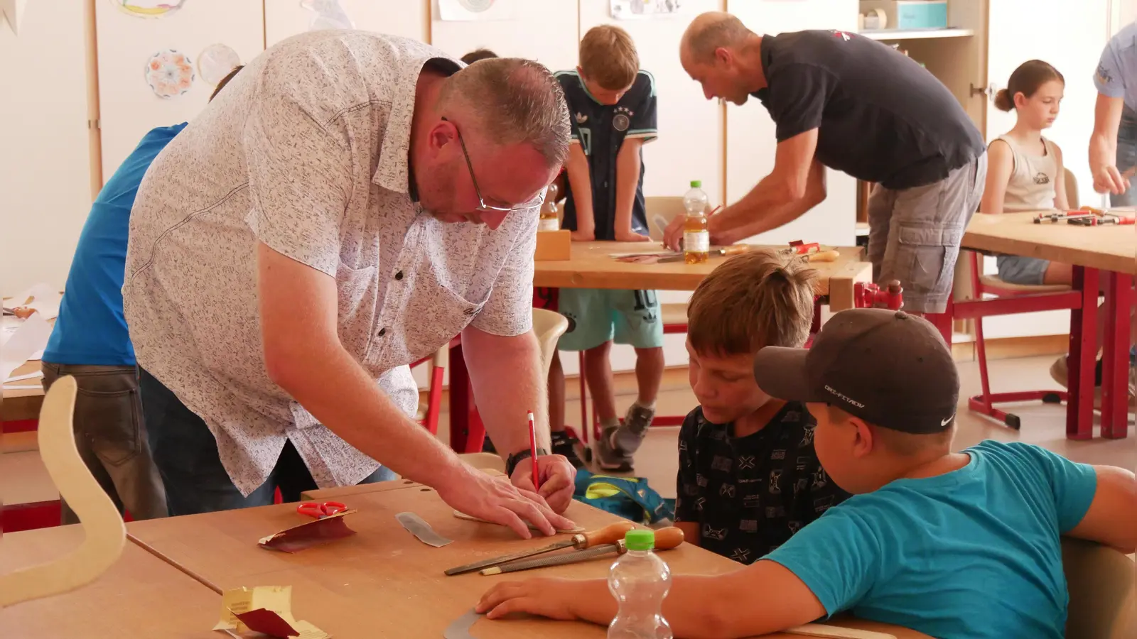 Die Kinder sind mit Feuereifer beim Bumerang-Bau. Hier geben Jeffrey Hausmann und Günther Simon (hinten) Hilfestellungen. (Foto: Daniel Ammon)