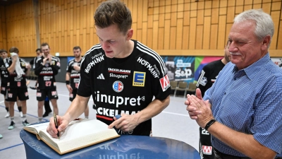 Christoph Steinert (links) vom HC Erlangen trägt sich ins Goldene Buch der Stadt Neustadt ein, der sportbegeisterte Bürgermeister Klaus Meier begutachtet das Szenario fast ein wenig andächtig. (Foto: Sportfoto Zink/Wolfgang Zink)