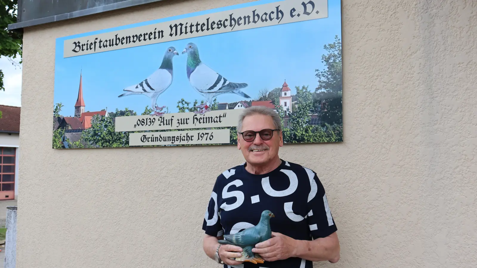 Schon seit Tag&nbsp;eins dabei: der Vorsitzende des Mitteleschenbacher Brieftaubenvereins, Ortwin Weiß. Zum 50. Geburtstag des Vereins ist ein neues Schild angefertigt worden. Die beiden Tauben auf dem Schild waren Weiß' erfolgreichste Weibchen. (Foto: Antonia Müller)