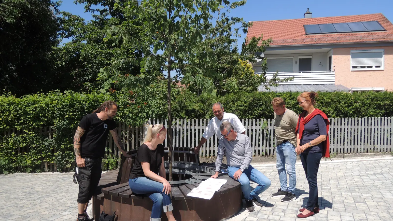 Über die jetzt abgeschlossene Sanierung des Sandwegs informierte Holger Hutmann (Zweiter von rechts) von der Bauverwaltung vor Ort (von links): Auf der Rundbank um die neue Linde sahen sich die Stadträte Michael Nowakowitsch (WwW) und Ilonka Sindel („Wir“/Grüne), zweiter Bürgermeister Walter Soldner, Rathauschef Patrick Ruh sowie Stadträtin Susanne Friedrich (SPD) die Planunterlagen an. (Foto: Peter Zumach)