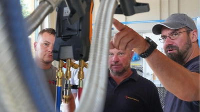 Meisterschüler Martin Scholz (r) unterhält sich mit Kollegen im Wärmepumpen-Labor auf dem Bildungs- und Innovationscampus der Handwerkskammer Potsdam (BIH). (Foto: Soeren Stache/dpa)