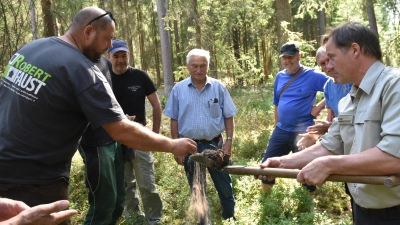 An Stellen innerhalb und außerhalb der Lichtung ließ Förster Gernot Käßer (rechts) die Waldbauern den Boden fühlen. Zuerst wurde eine staubtrockene Probe außerhalb vorgeführt. (Foto: Anita Dlugoß)