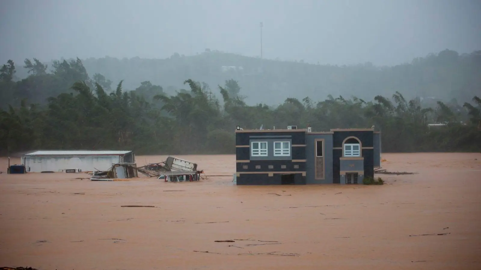 Drei Menschen warten in einem Haus auf Rettung vor den Überschwemmungen, die Hurrikan „Fiona“ in Puerto Rico verursacht hat. (Foto: Stephanie Rojas/AP/dpa)