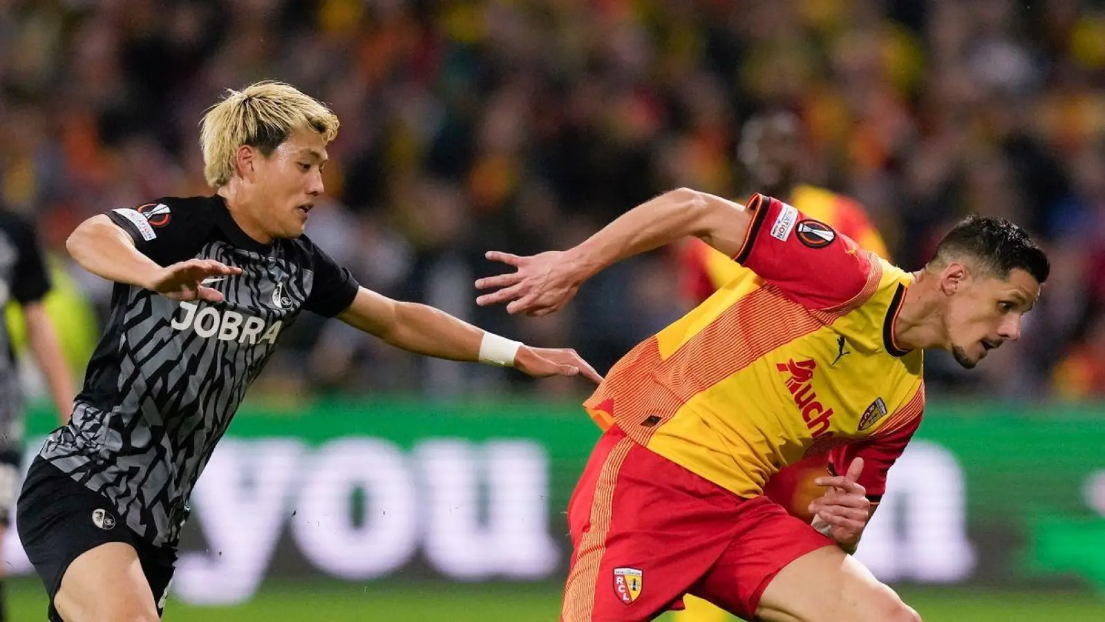 Ritsu Doan (l) und der SC Freiburg wollen gegen Lens bestehen. (Foto: Thibault Camus/AP/dpa)