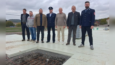 Im Vordergrund schimmert die Zeitkapsel im Boden: Oberscheinfelds Bürgermeister Peter Sendner (Zweiter von rechts) mit weiteren Beteiligten bei der offiziellen Grundsteinlegung für das neue Feuerwehrhaus. (Foto: Florian Jennemann)