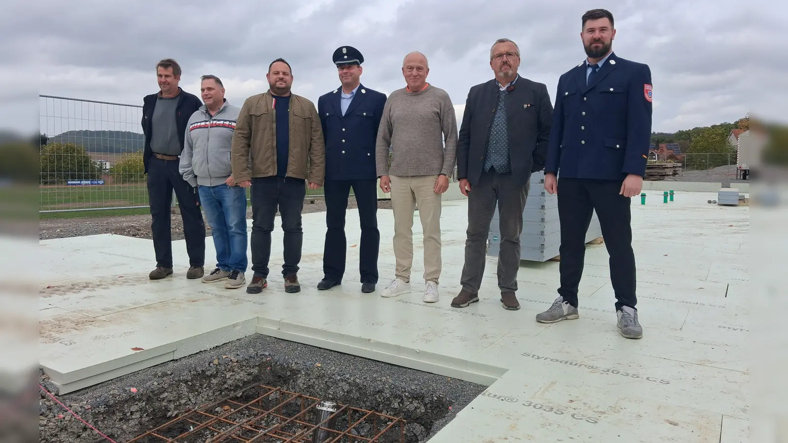 Im Vordergrund schimmert die Zeitkapsel im Boden: Oberscheinfelds Bürgermeister Peter Sendner (Zweiter von rechts) mit weiteren Beteiligten bei der offiziellen Grundsteinlegung für das neue Feuerwehrhaus. (Foto: Florian Jennemann)