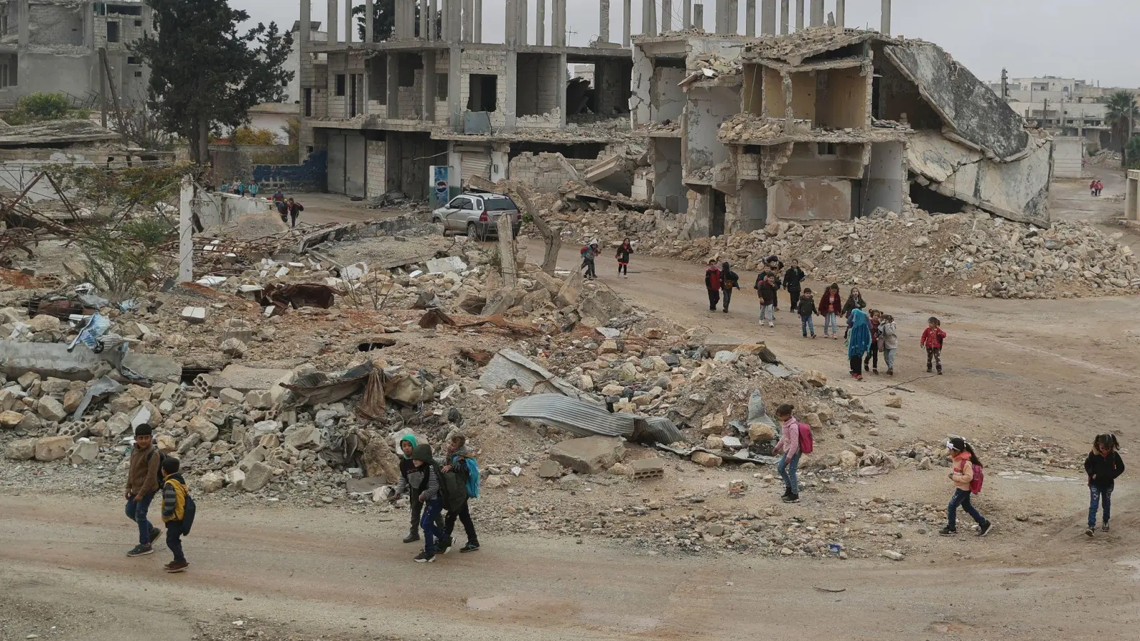 Alltag in Syrien: Kinder auf dem Rückweg von der Schule - sie laufen an Gebäuden vorbei, die durch Luftangriffe zerstört wurden. (Foto: Anas Alkharboutli/dpa)