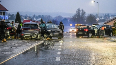 Nach einem Unfall bei Glatteis mit mehreren Fahrzeugen in Baden-Württemberg stehen Helfer und Beteiligte an den Autos auf einer Straße.  (Foto: Jason Tschepljakow/dpa)