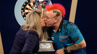 Peter Wright feiert mit seiner Frau Joanne und der Sid Waddell Trophy seinen Sieg. (Foto: John Walton/PA Wire/dpa)