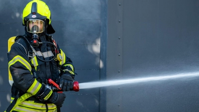 Ein Mitglied der Feuerwehr beim Löscheinsatz. (Foto: David Inderlied/dpa/Symbolbild)