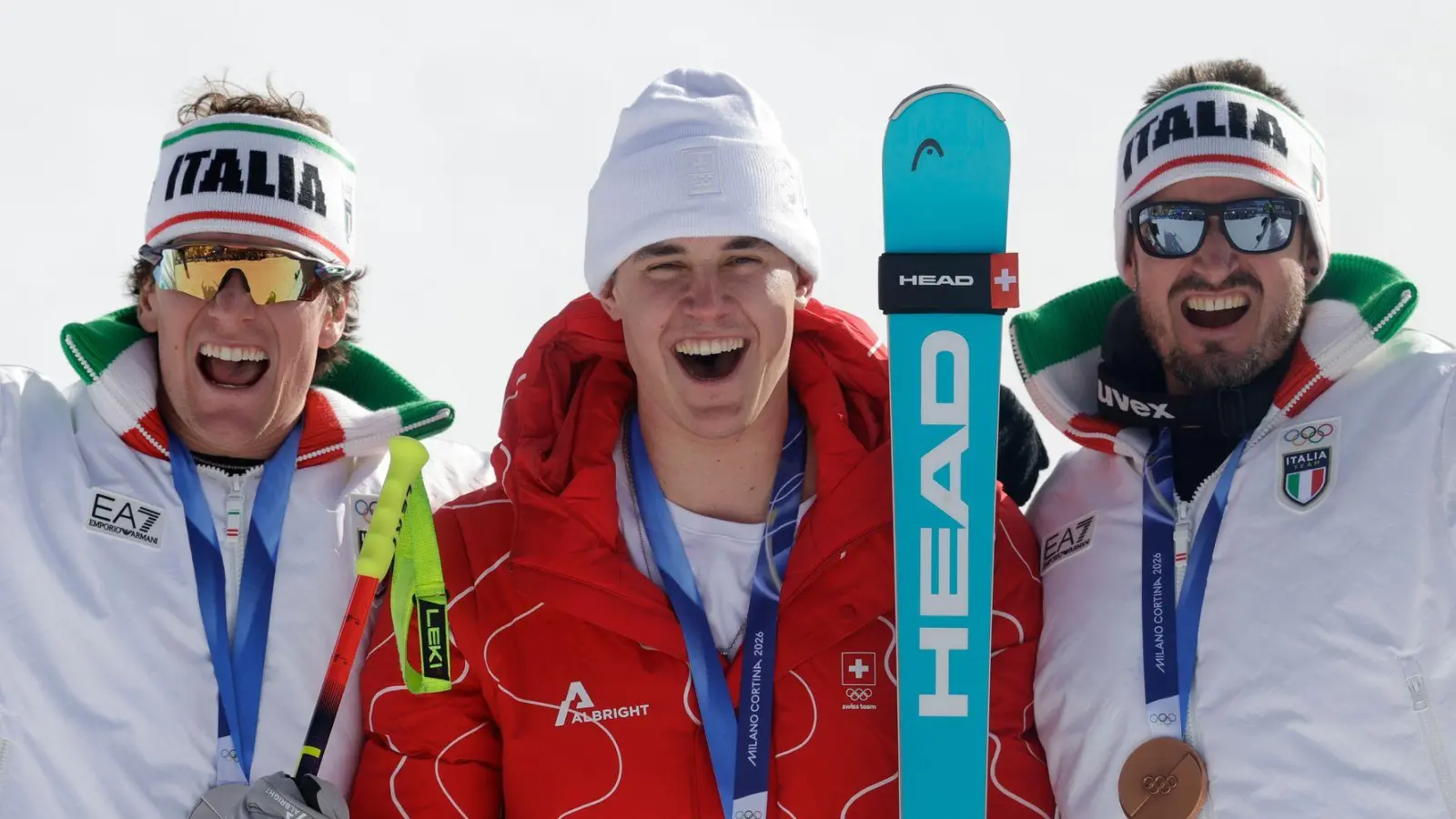 Olympiasieger Franjo von Allmen wird flankiert von Silber-Gewinner Giovanni Franzoni (links) und dem Drittplatzierten Dominik Paris. (Foto: Oliver Weiken/dpa)