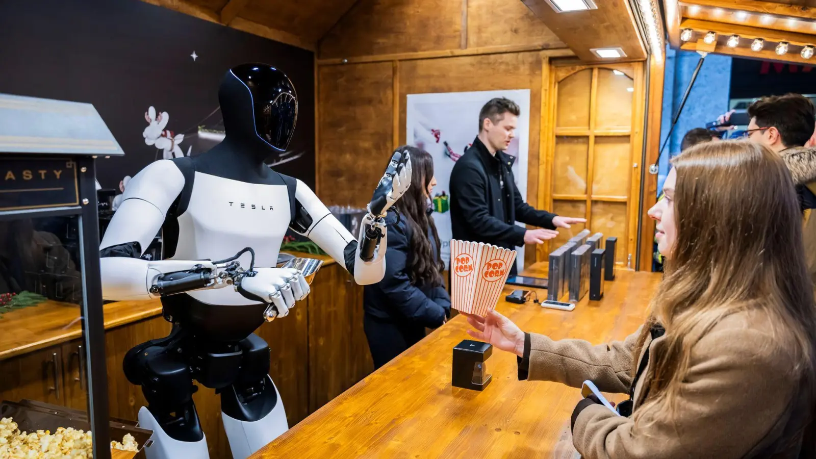 Der humanoide Roboter „Optimus“ von Tesla verteilt bei seiner Vorstellung in der Mall of Berlin Popcorn an eine Besucherin. (Foto: Christoph Soeder/dpa)