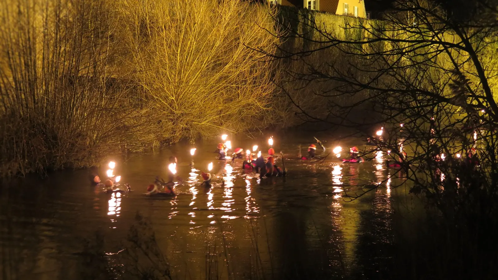 Vor Dinkelsbühls Stadtmauer als imposanter Kulisse: Bei einer Wassertemperatur um die vier Grad legten die Fackel-Schwimmerinnen und Fackelschwimmer rund einen Kilometer in der Wörnitz zurück. (Foto: Alexander Schäffer)