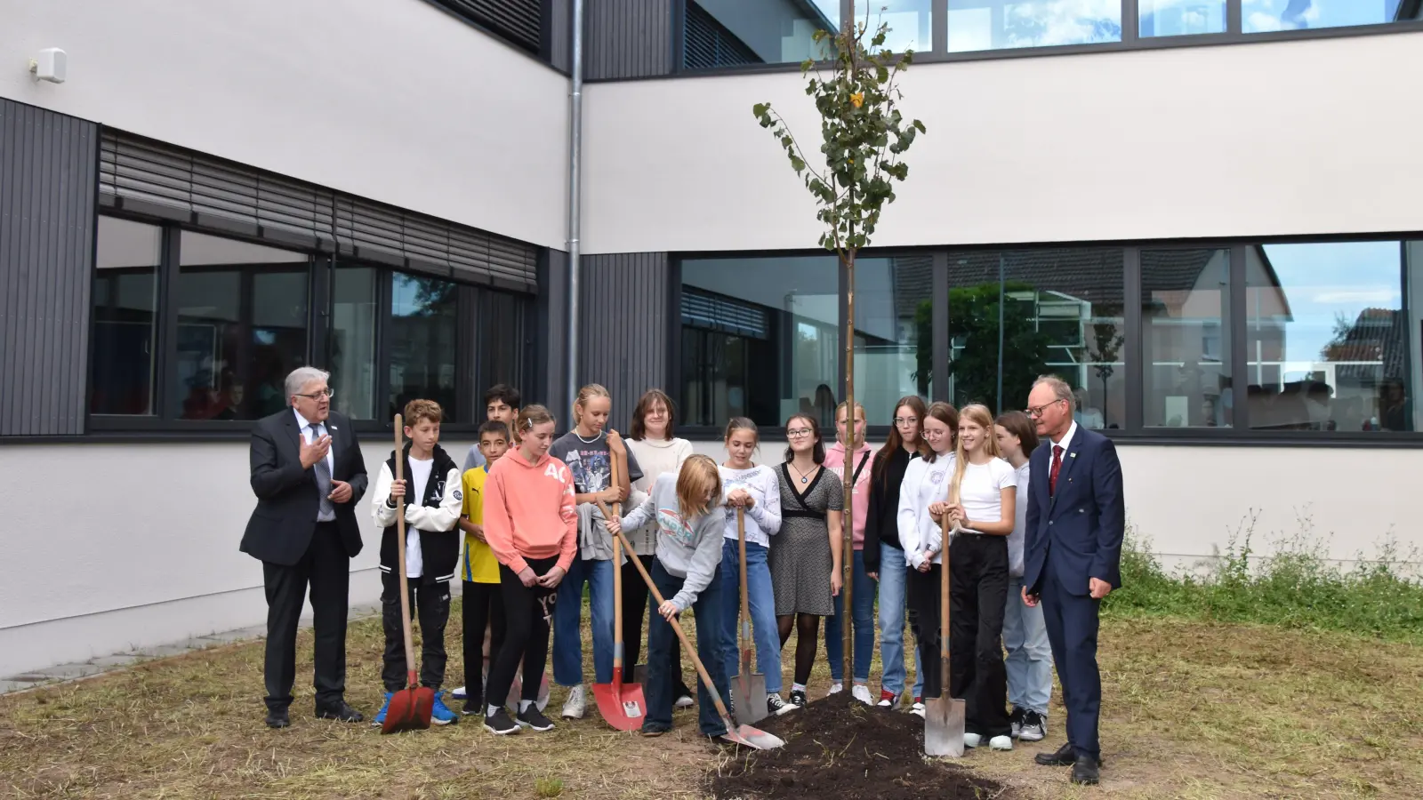 Eine Winterlinden-Pflanzung – um den Baum wird sich eine Ethik-Klasse kümmern – stand am Abschluss der Einweihungsfeier mit Landrat Helmut Weiß (links) und Direktor Wolfram Schröttel. (Foto: Andreas Reum)