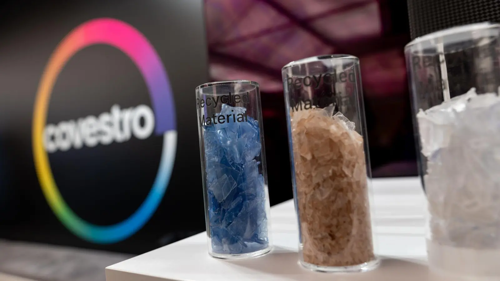 Eine deutsche Firma wird arabisch: Das Logo des Spezialchemie-Konzerns in einem Firmen-Showroom, davor Gläser mit Covestro-Materialien.  (Foto: Fabian Strauch/dpa)