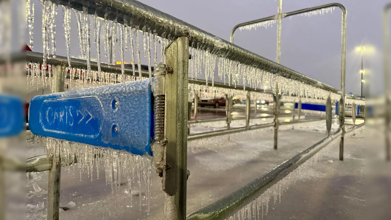 Eiszapfen hängen an einem Geländer während eines Wintersturms auf einem Parkplatz. (Foto: John Raby/AP/dpa)