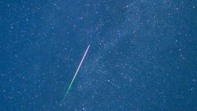 Ein Meteor mit grünem Schweif ist in der Nacht zu Donnerstag am Sternenhimmel zu sehen.  (Foto: Patrick Pleul/dpa)