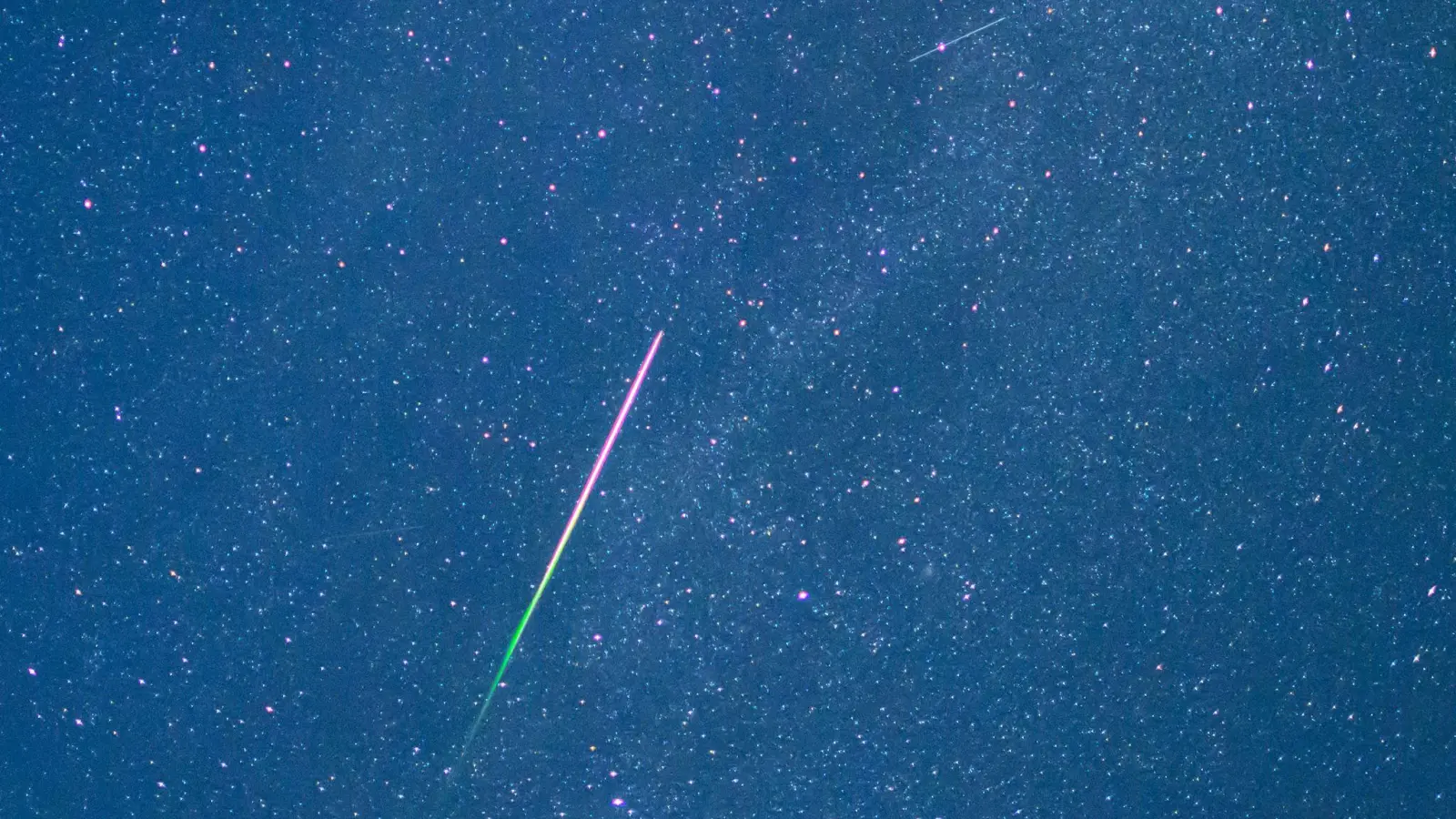 Ein Meteor mit grünem Schweif ist in der Nacht zu Donnerstag am Sternenhimmel zu sehen.  (Foto: Patrick Pleul/dpa)